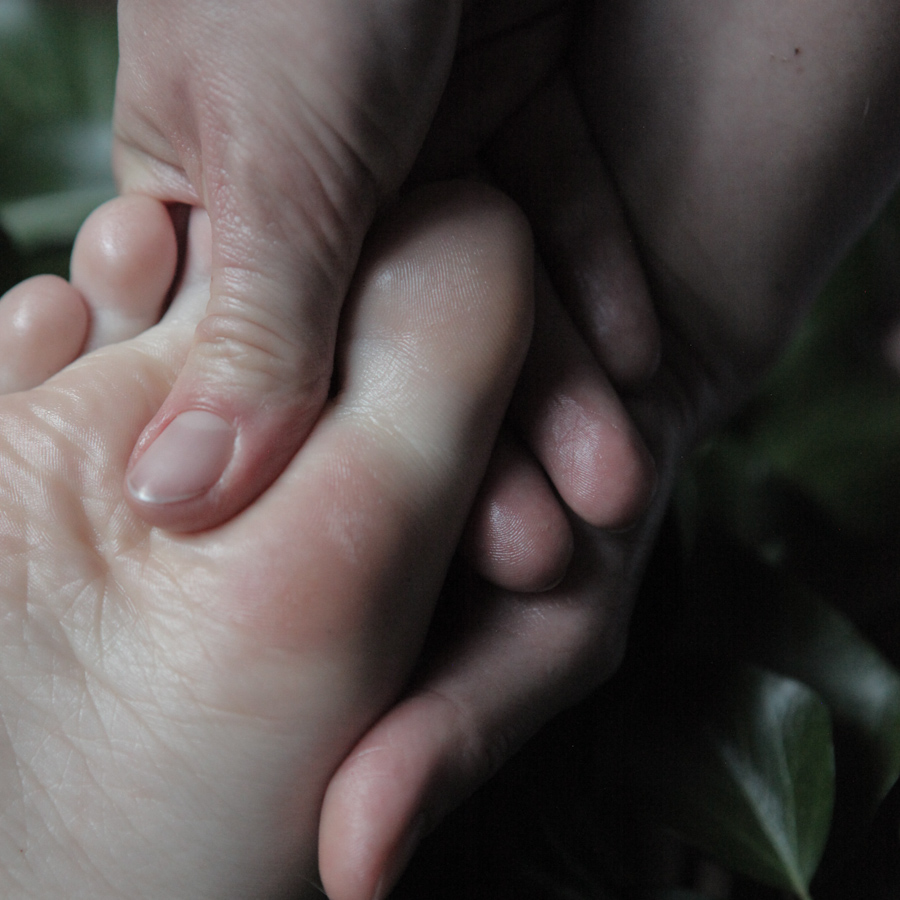 dłonie masażyści obejmujące stopę klienta